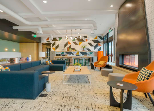 a lobby with blue couches and orange chairs and a fireplace