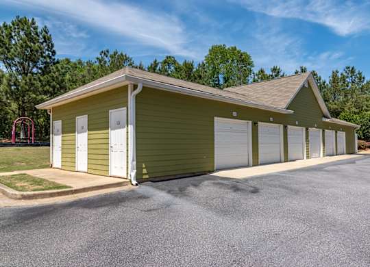 Apartments in Opelika for Rent – The Crossings of Opelika - a row of garages in front of a grassy area with trees in the background