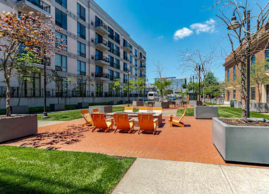 A sunny day at a courtyard with orange chairs and a white table.