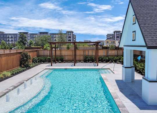Heights, Houston, TX, Homes For Rent with In-Unit Washer and Dryer - The Crossing at Timbergrove - Swimming Pool with Fountains, a Shaded Area Surrounded by a Wood Fence.