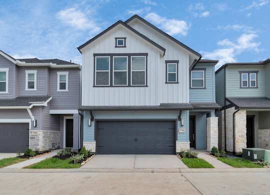 Heights, Houston TX Houses for Rent - The Crossing at Timbergrove - Home Exterior with Grey and White Walls, a Garage, Front Drive, and Landscaped Plant Beds, From Street View