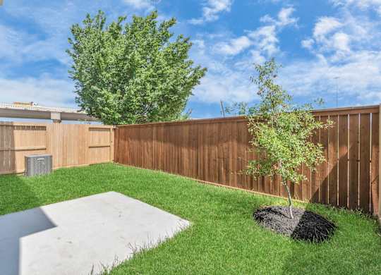 a backyard with green grass and a wooden fence