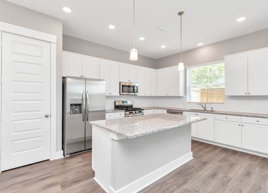 a kitchen with white cabinets and a large island with granite countertops