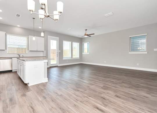 a kitchen and living room with hardwood floors and a chandelier