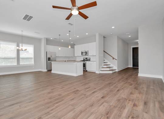 Dog-Friendly homes for rent in Heights, Houston TX - The Crossing at Timbergrove - Open-Concept, Empty Living Space with Hanging Lights, a Ceiling Fan, Windows, Hardwood-Inspired Flooring, and a View 