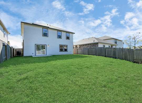 Houston, TX Single-Family Homes for Rent - Imperial Forest - A Backyard with a Small Concrete Patio, Green Lawn Enclosed by a Wooden Privacy Fence.