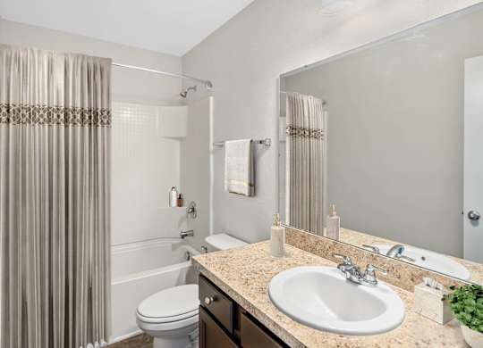 A bathroom with a toilet, sink, and shower curtain.