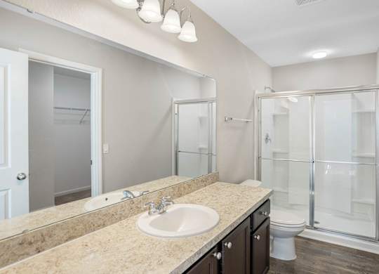 A bathroom with a sink, mirror, and shower.