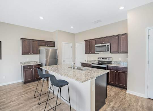 A kitchen with a white island and dark brown cabinets.