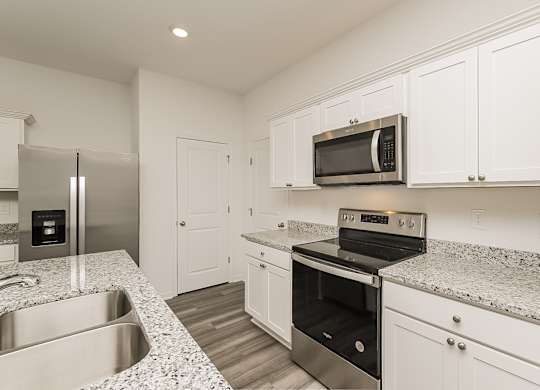 A kitchen with a stainless steel refrigerator, microwave, oven, and sink.