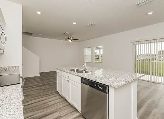 A modern kitchen with a stainless steel dishwasher and a ceiling fan.