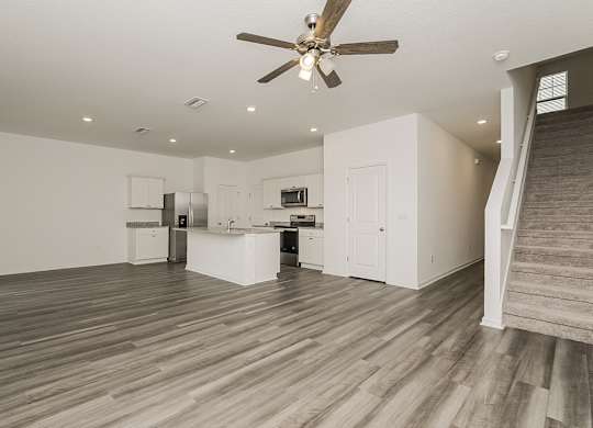 A spacious room with a ceiling fan and wooden flooring.