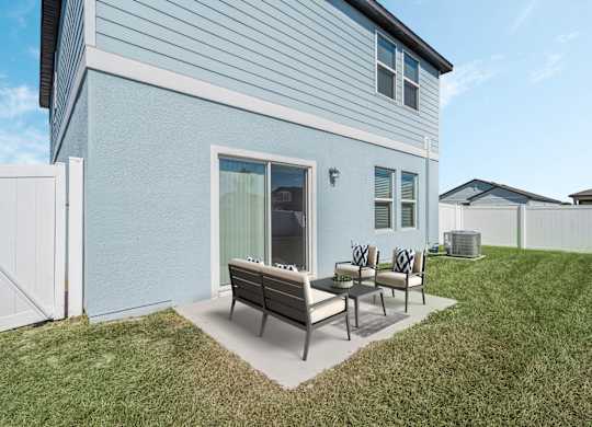 A blue house with a white fence and a patio with a table and chairs.