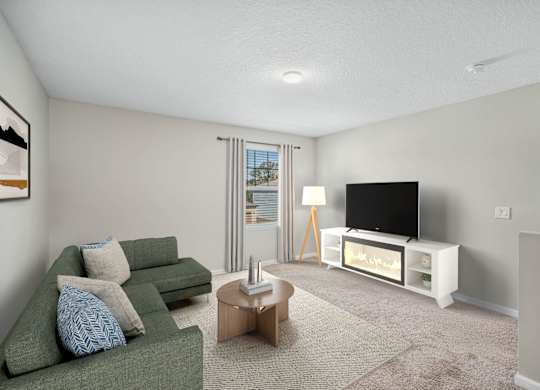 A living room with a green couch, a coffee table, and a television.