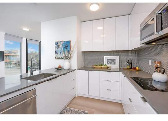 Fremont Apartments for Rent - Inspire Fremont - Kitchen with Stainless Steel Appliances, Granite Countertops, White Cabinets, and Hardwood Style Flooring
