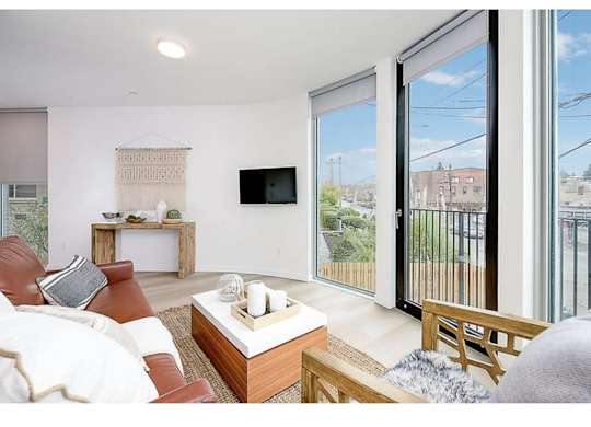 Apartments In Seattle, WA For Rent - Inspire Fremont - Living Room With Floor-To-Ceiling Windows, Hardwood-Style Flooring, And A Large Sofa.