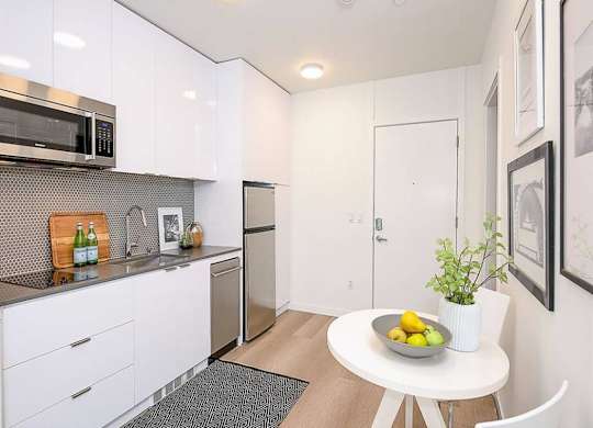 Apartments in Seattle, WA for Rent - Inspire Fremont - Kitchen with a Dining Area, White Modern Cabinets, and Stainless-Steel Appliances