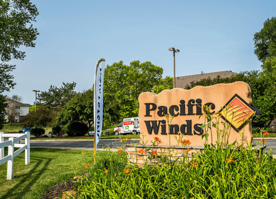 a welcome sign for Pacific Winds in front of an apartment building