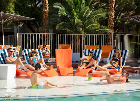 People relaxing on sun loungers by a pool.
