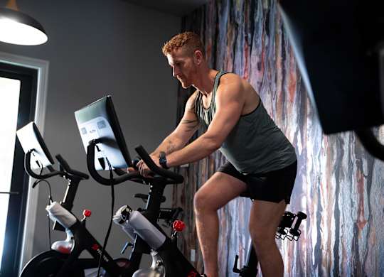 A man is working out on a stationary bike in a room.