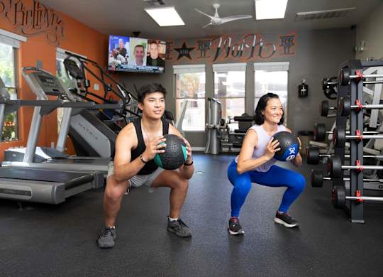 A man and a woman are exercising in a gym.