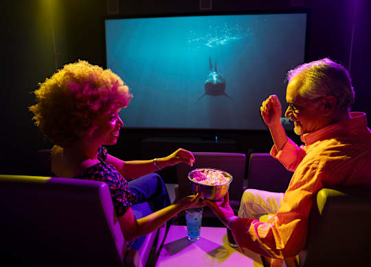 A man and a woman are watching a shark movie in a cinema.