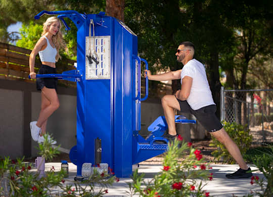 A woman in a white top and black shorts is jumping into a blue water fountain. at The 95 Apartments, Nevada, 89129
