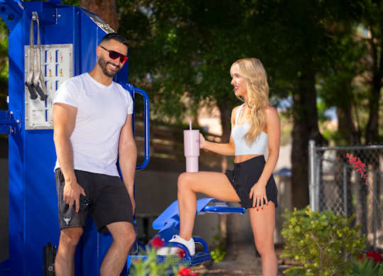 A man and a woman are sitting on a blue bench in a park. at The 95 Apartments, Las Vegas, NV, 89129