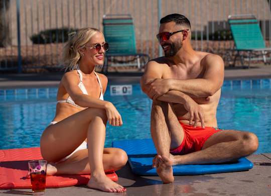 A man and a woman are sitting by a pool. at The 95 Apartments, Las Vegas