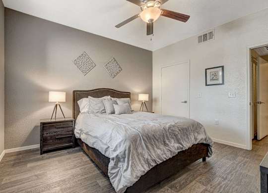 A bedroom with a bed, nightstand, and a ceiling fan.