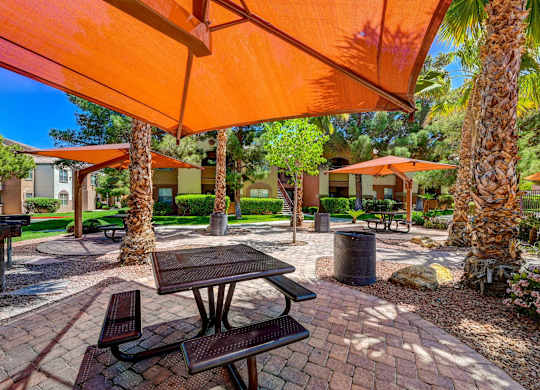 A patio with a table and chairs under an orange umbrella.