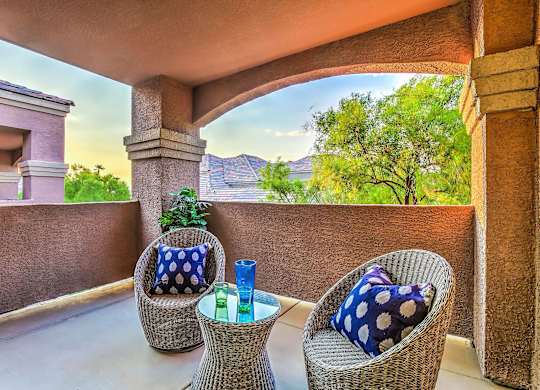 A patio with two chairs and a table with a blue pillow on it.