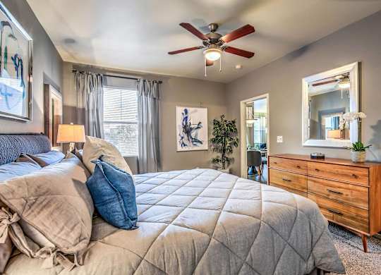 A bedroom with a large bed and a ceiling fan.