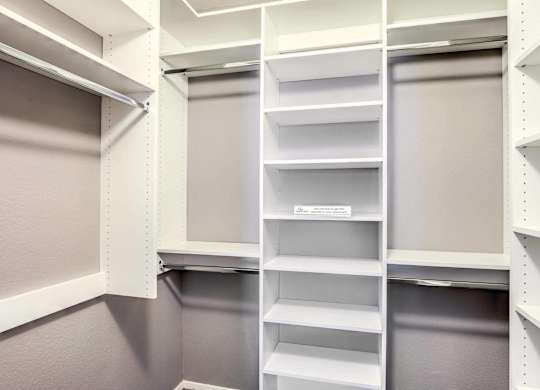 A white pantry with shelves and a grey door.