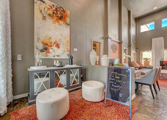 A room with a large painting on the wall and a chalkboard sign on the side table.