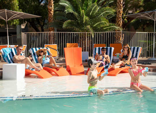 People are relaxing by the poolside on sun loungers.