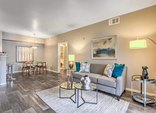 A living room with a grey couch, a coffee table, and a painting on the wall.