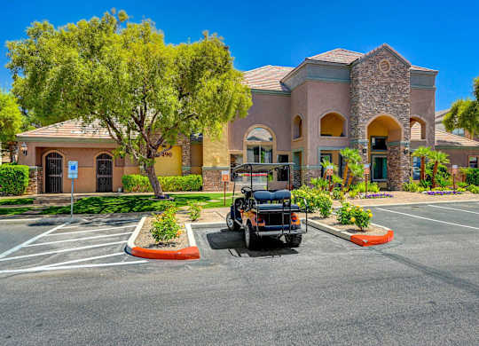 A black golf cart is parked in a parking lot in front of a building.