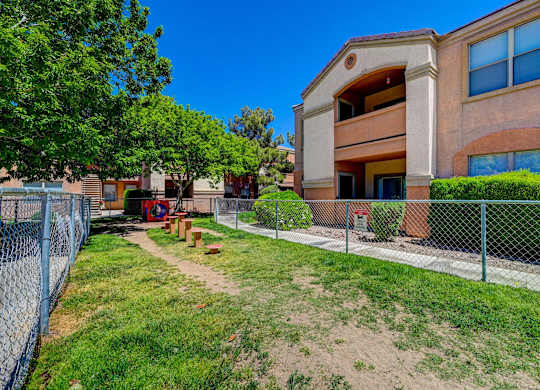 A building with a fence and a green lawn in front.
