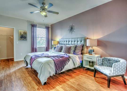 A bedroom with a bed, chair, and a ceiling fan.
