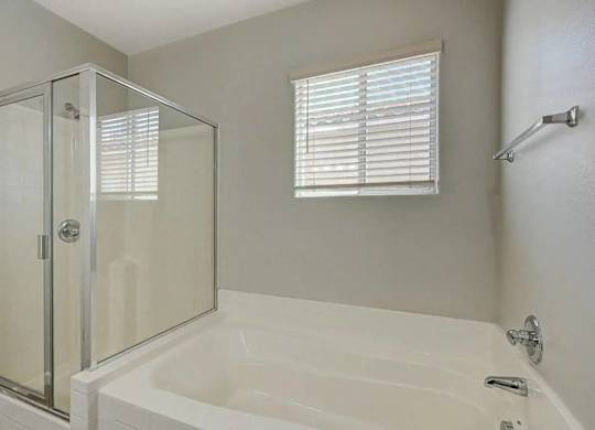 A white bathtub with a glass shower door in a bathroom. at Habitat @ DTLV, Las Vegas, NV