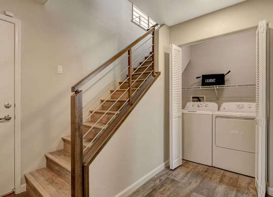 A staircase with a wooden handrail leads to a laundry room with a washer and dryer. at Habitat @ DTLV, Las Vegas