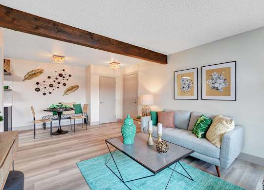 A living room with a grey couch and a glass coffee table.