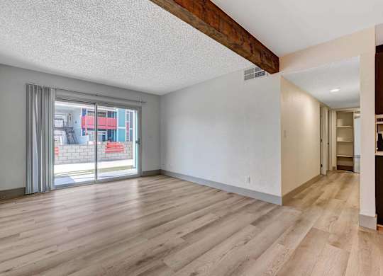 A room with wooden flooring and a sliding glass door.