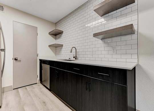 A kitchen with black cabinets and white subway tiles.
