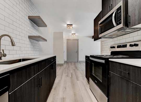 A kitchen with black cabinets and a white tiled backsplash.