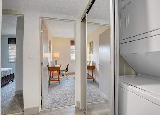 A white refrigerator is in the kitchen area of a small apartment.