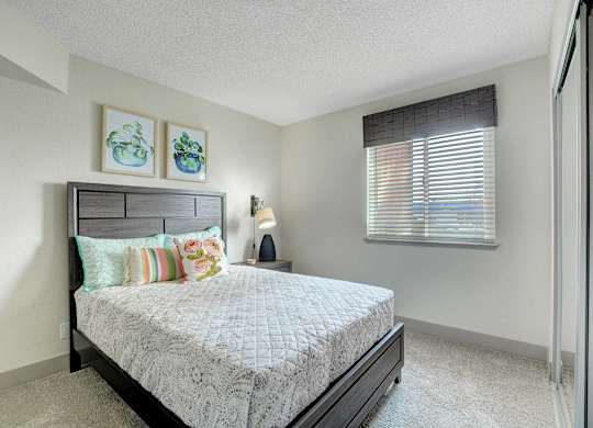 A bedroom with a bed, pillows, and a nightstand.