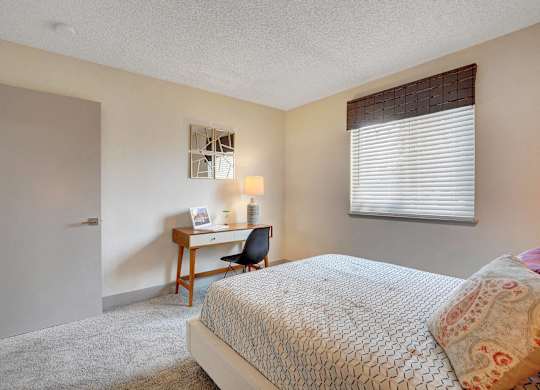A bedroom with a bed, desk, and chair.