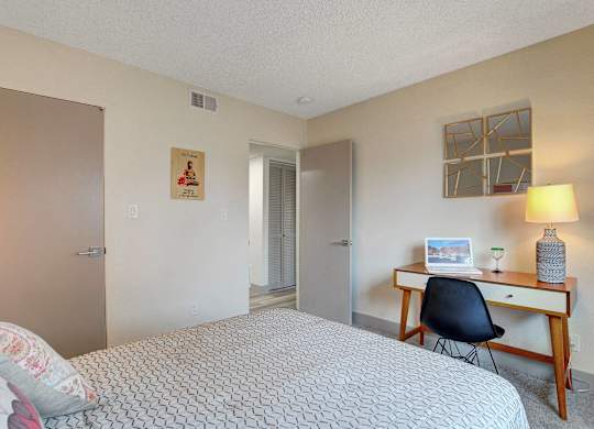A bedroom with a bed, desk, and chair.